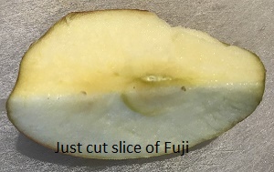 A just-cut slice of Fuji apple